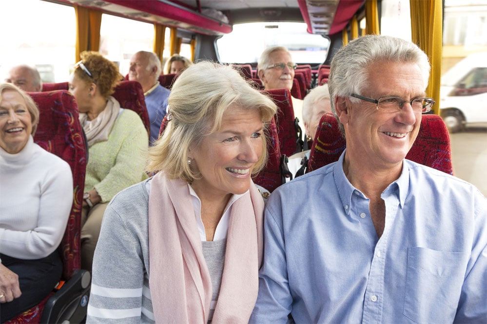 Couple souriant qui regarde par la fenêtre d'un autocar