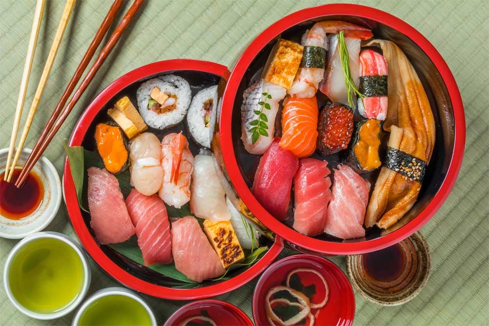 Assiette de sushi japonais accompagnée de baguettes et de bols de riz.