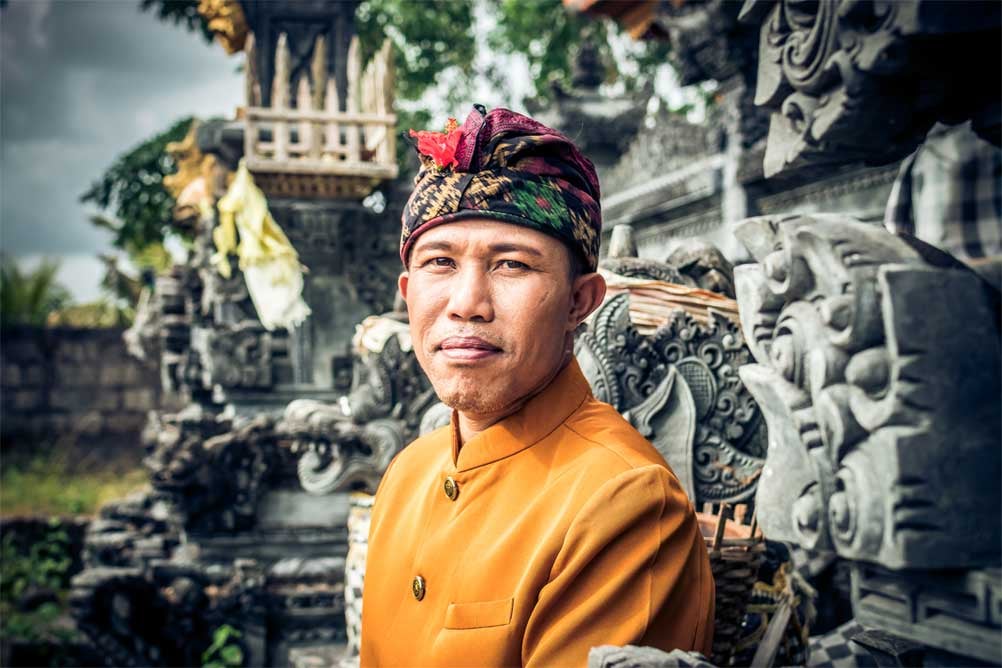 Homme en tenue traditionnelle devant un temple à Bali
