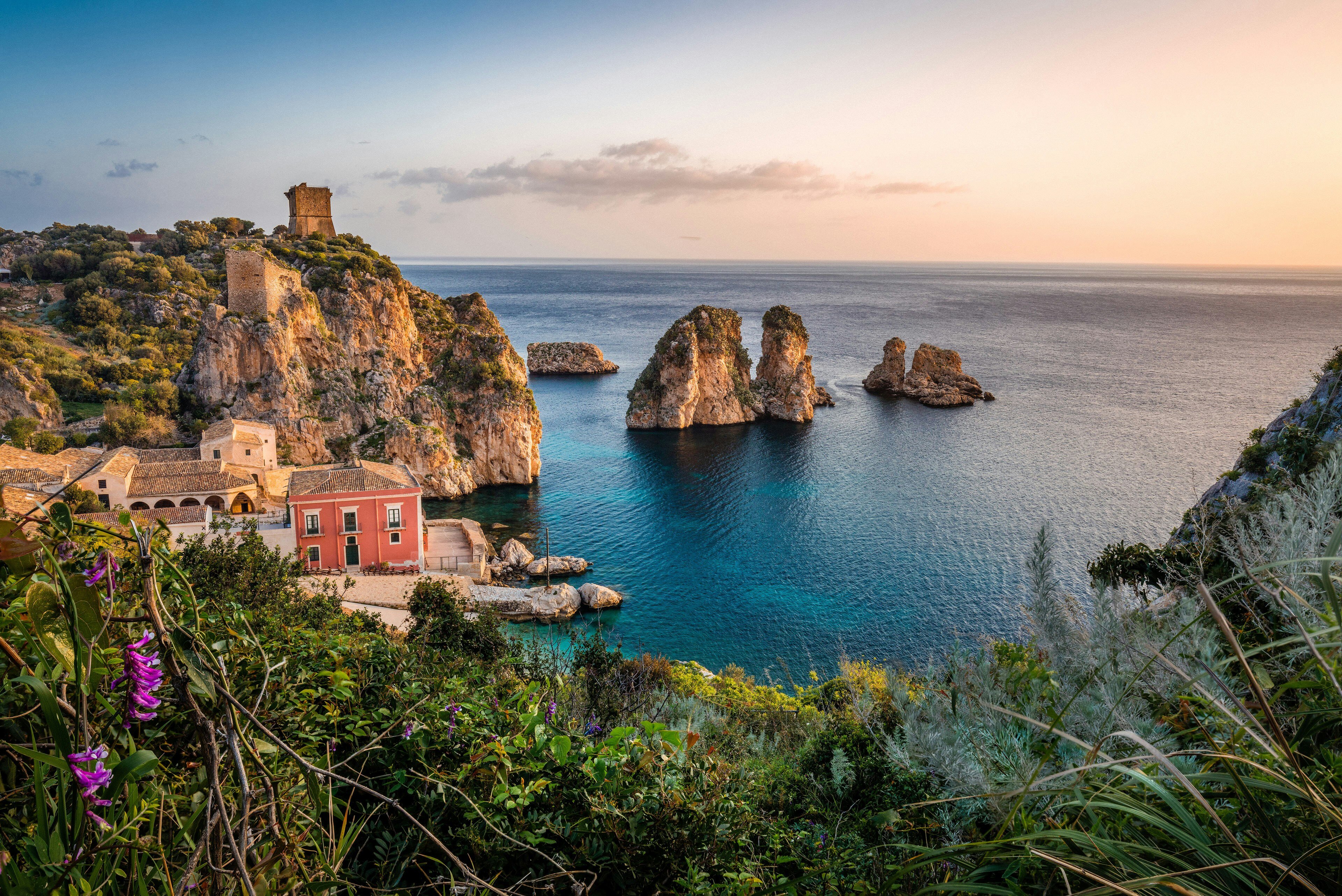 Bord de mer italien avec de la verdure, une falaise, des rochers et des bâtiments colorés